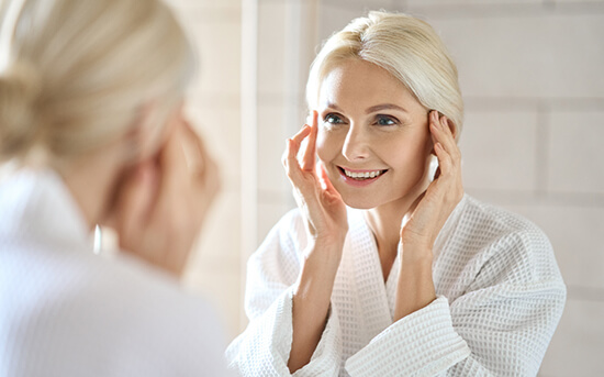 Woman smiling in the mirror after oculoplastic surgery